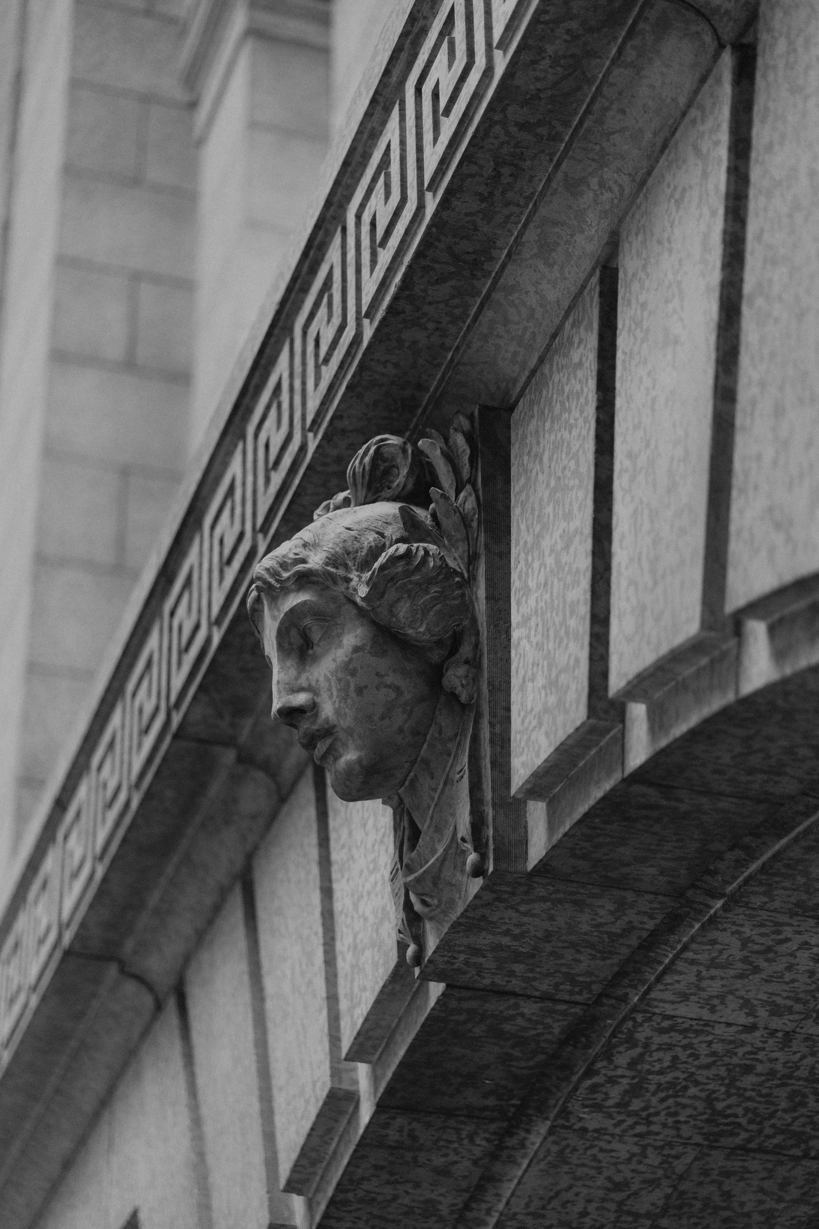 Detail of a stone carved woman's face keystone on the exterior of the Manitoba Legislative Building, Winnipeg — black and white, classical architectural detail, by Ngo Photography