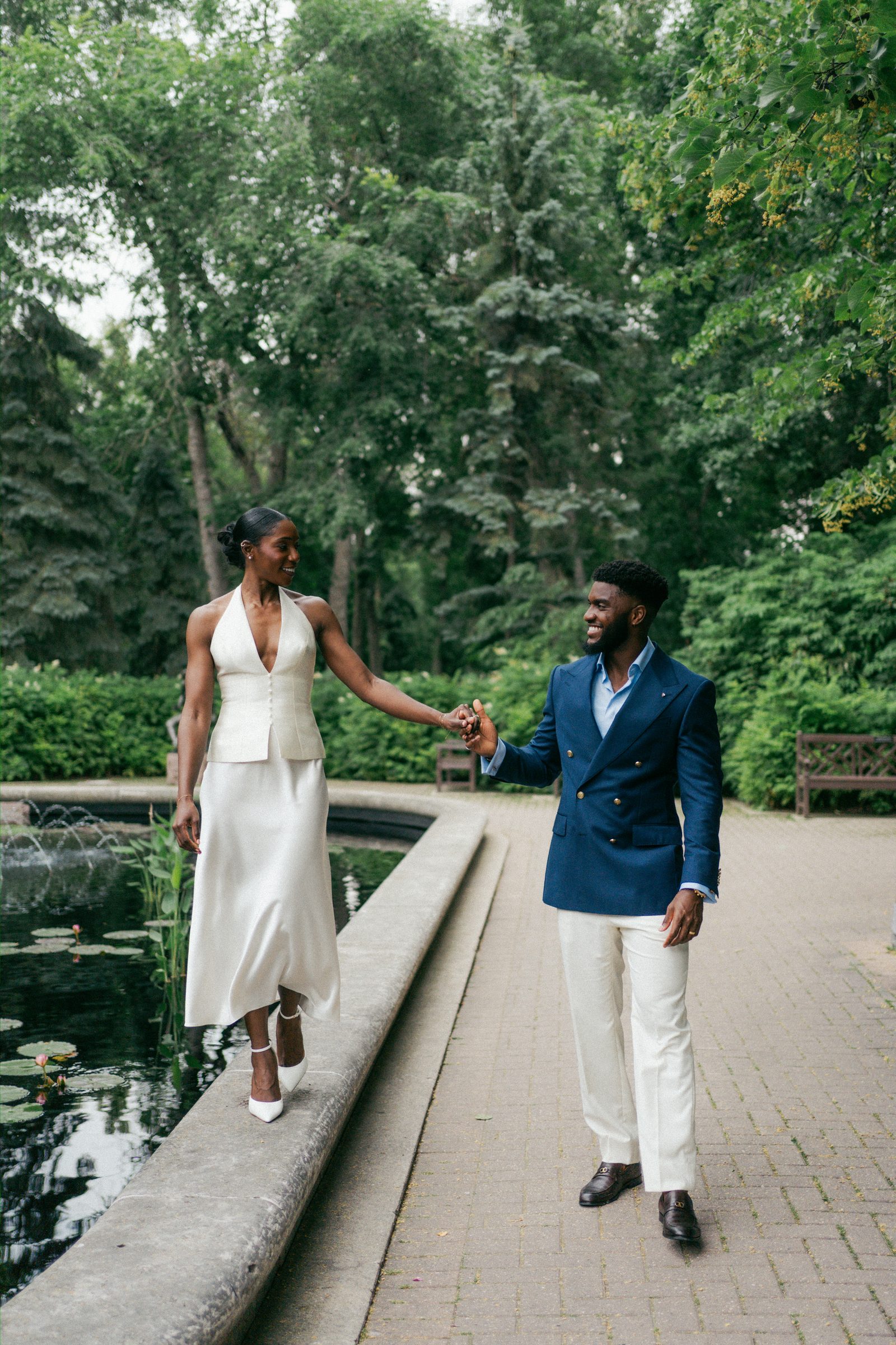 Film-style portrait of Tobi and Emeka laughing together at Leo Mol Sculpture Garden — Assiniboine Park, Winnipeg micro-wedding photography
