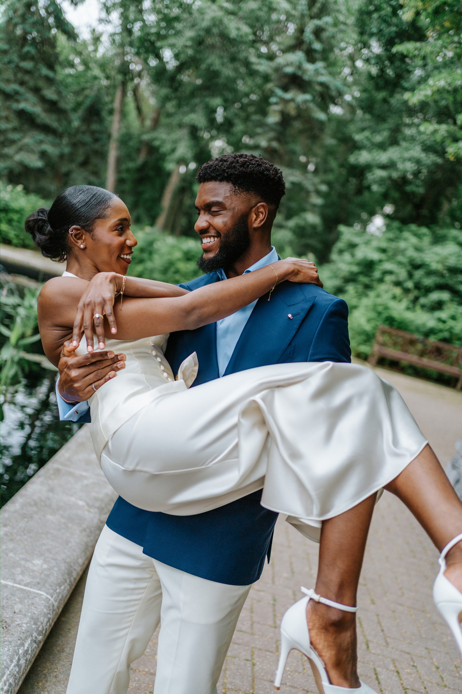Tobi and Emeka together by the lily pond at Leo Mol Sculpture Garden in Assiniboine Park — couple portrait in the lush July garden, Winnipeg