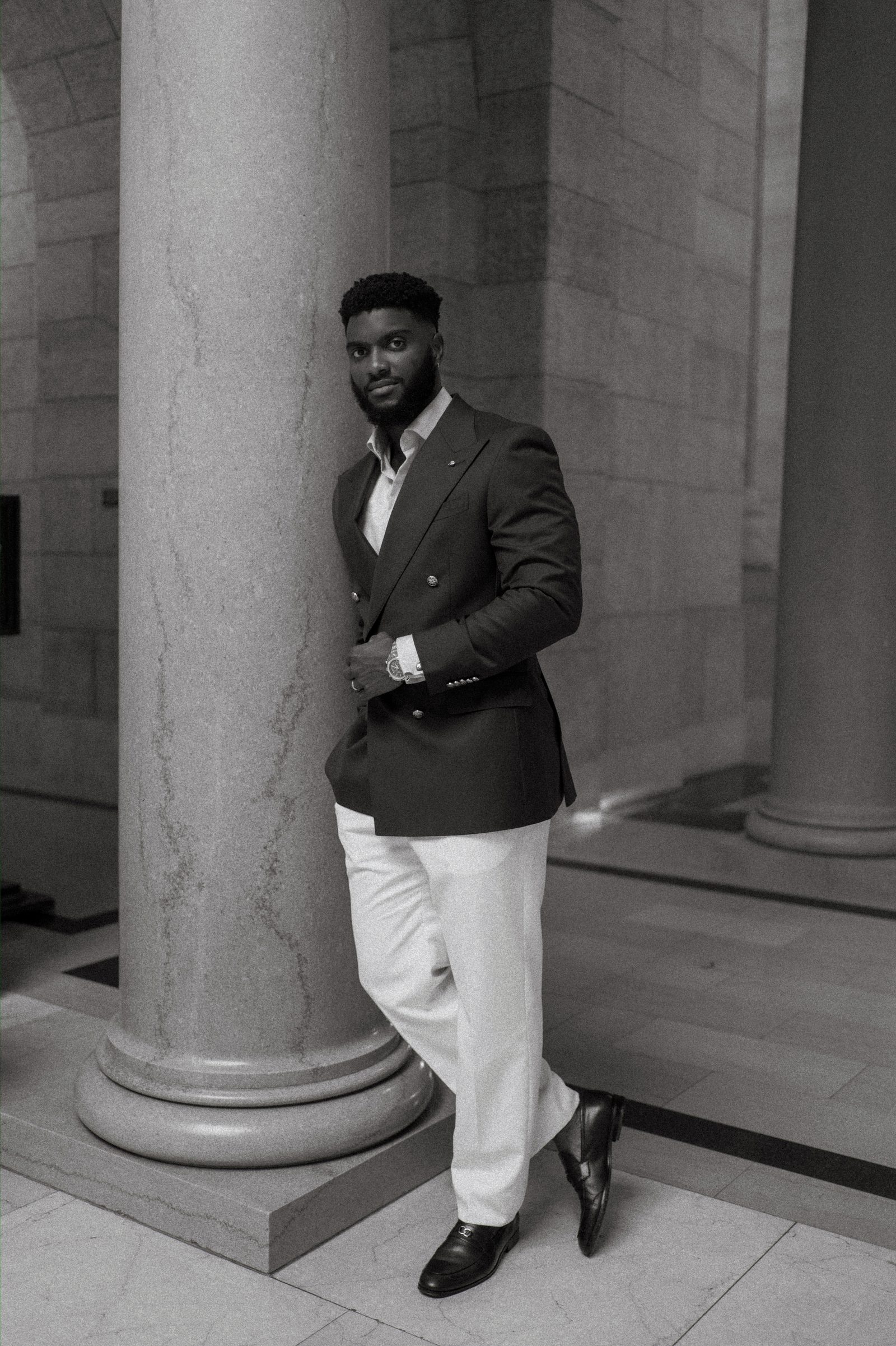 Tobi and Emeka in front of the Manitoba Legislative Building exterior colonnade — wide couple portrait with classical stone architecture, Winnipeg wedding photographer