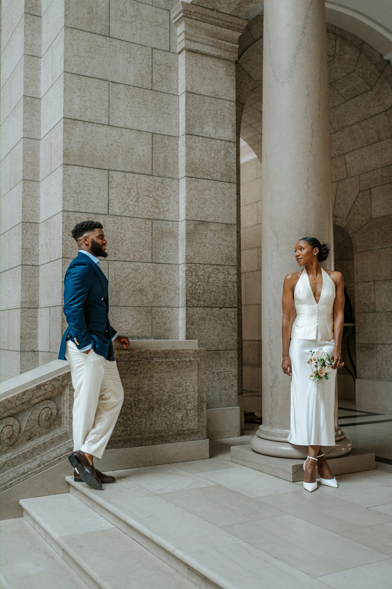 Emeka and Tobi on the Legislative Building exterior steps — editorial fashion-forward couple portrait between stone pillars, Winnipeg