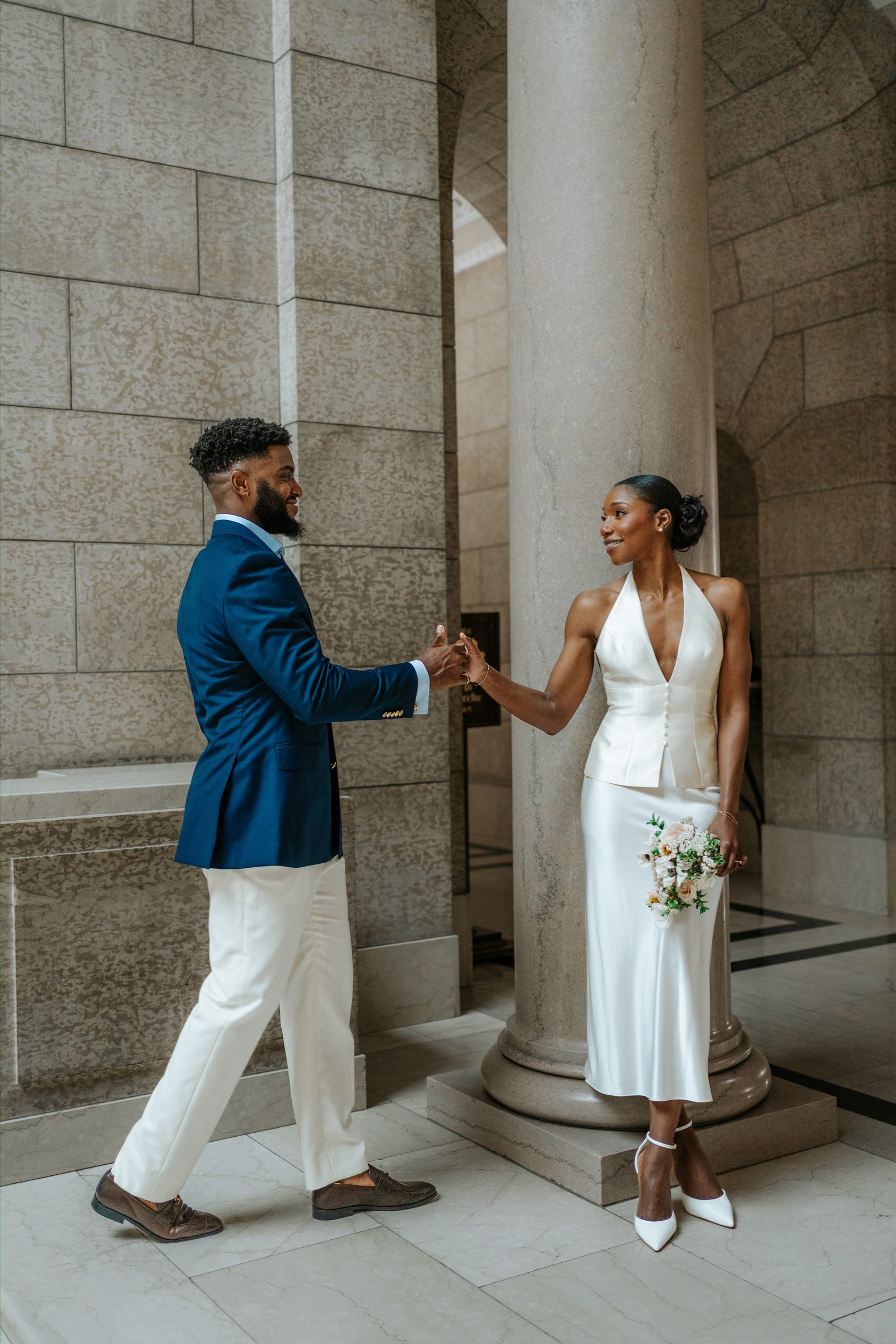 Tobi and Emeka on the exterior steps of the Manitoba Legislative Building — intimate close couple portrait with stone columns, Winnipeg